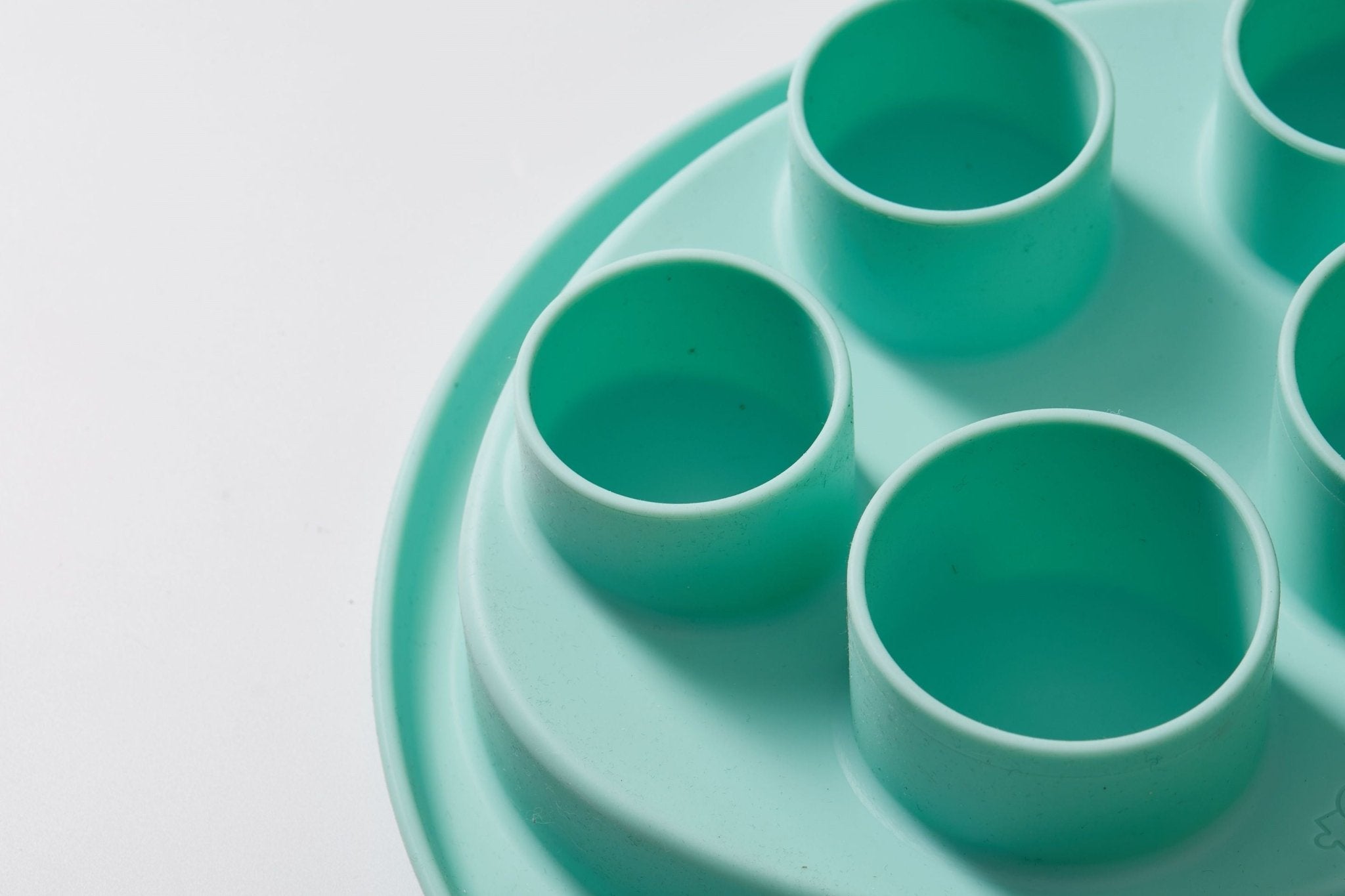 Close-up of a Lawn-Green Puzzle Digger by Puzzle Feeder™, crafted from non-toxic silicone and featuring round compartments, displayed on a white surface.