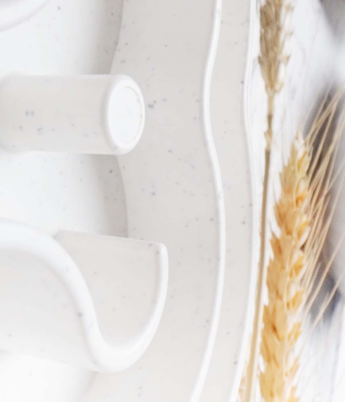 Close-up view of a white speckled ceramic bowl adorned with curved designs and a wheat pattern on a section, inviting you to slow down and appreciate its intricate details.