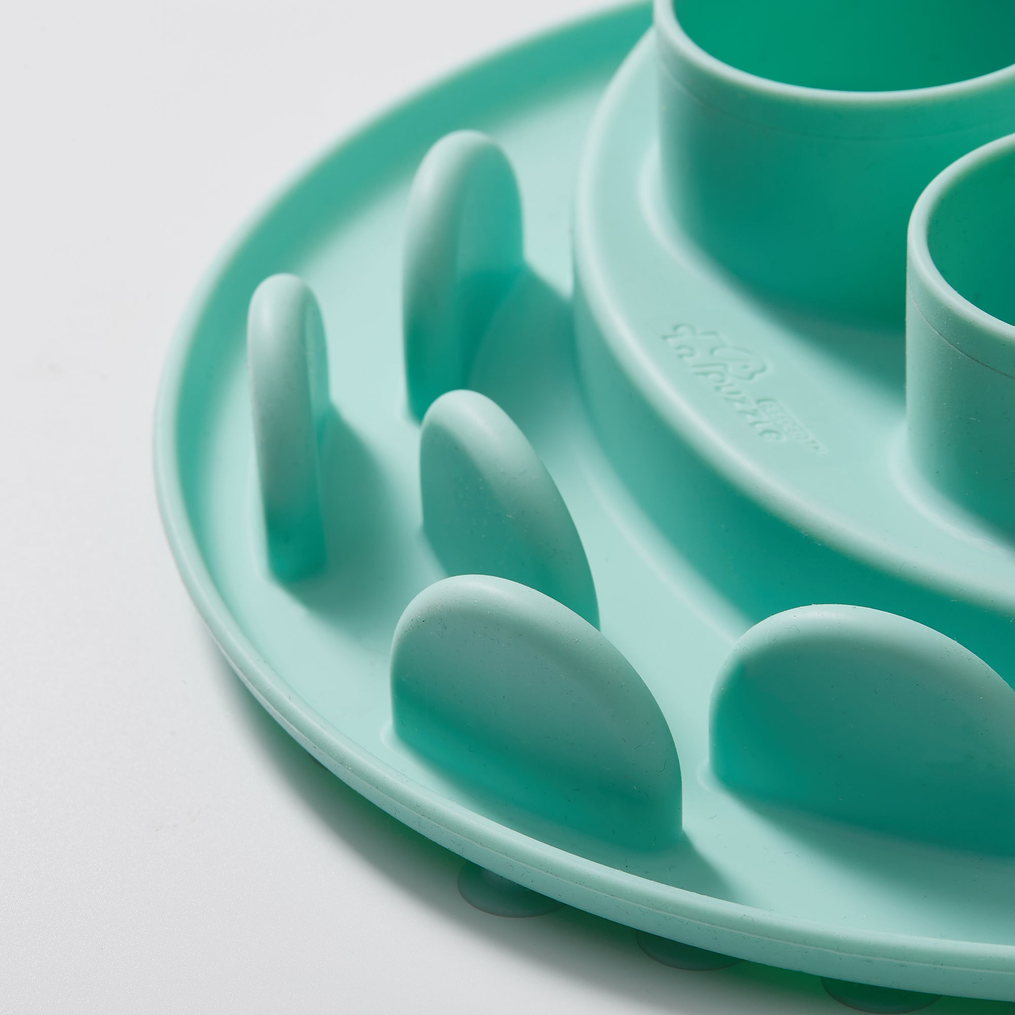 Close-up of a lawn-green Puzzle Digger by Puzzle Feeder™, featuring ridges and cylindrical shapes, made from non-toxic materials. This biomimetic design, ideal as a pet feeding mat or toy, gently stimulates your cat's hunting instincts against a pristine white background.