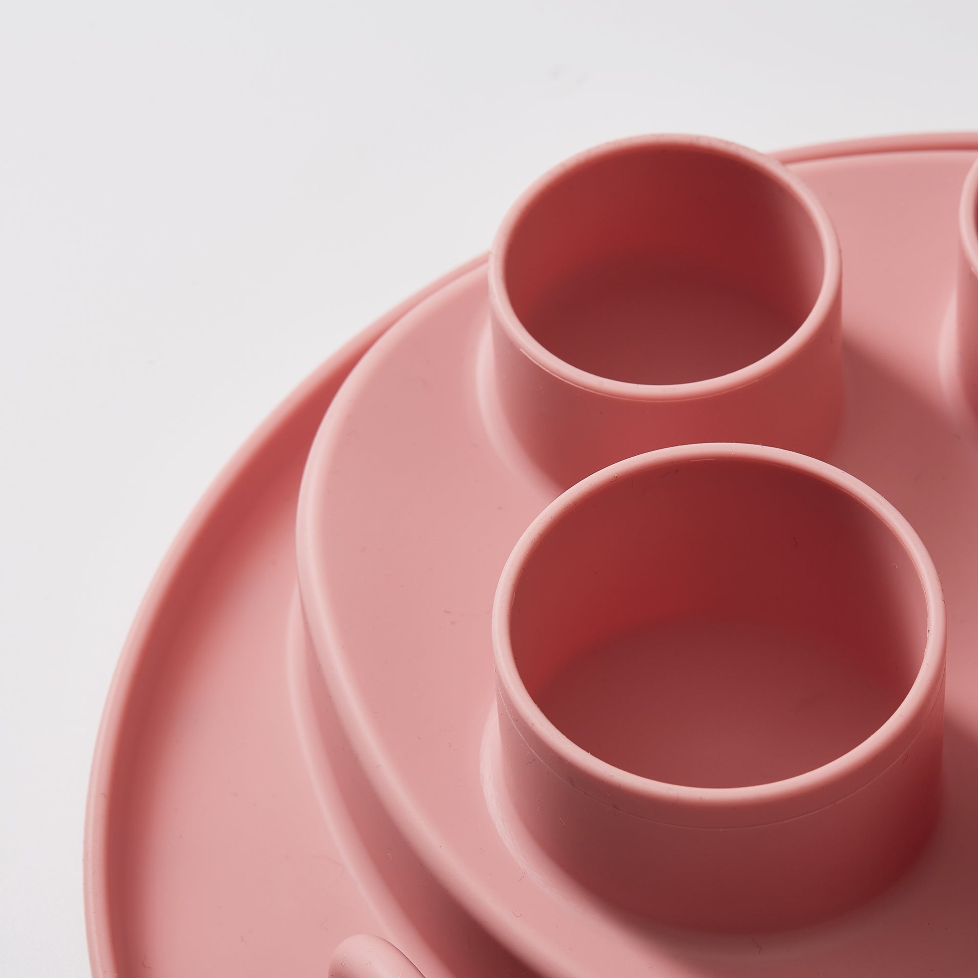 Close-up of the Puzzle Digger - For Cat Hunting Instinct in coral-pink by Puzzle Feeder™, featuring a circular design with several cylindrical compartments, on a white background.