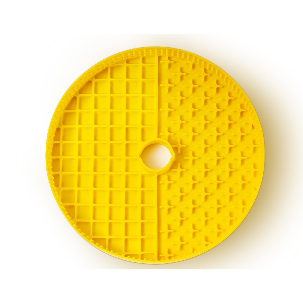 The Dog Licking Mat Accessory from Puzzle Feeder™, designed as a round yellow plastic waffle leaf clay cutter with a grid pattern and central hole, functions as an innovative puzzle feeder accessory.