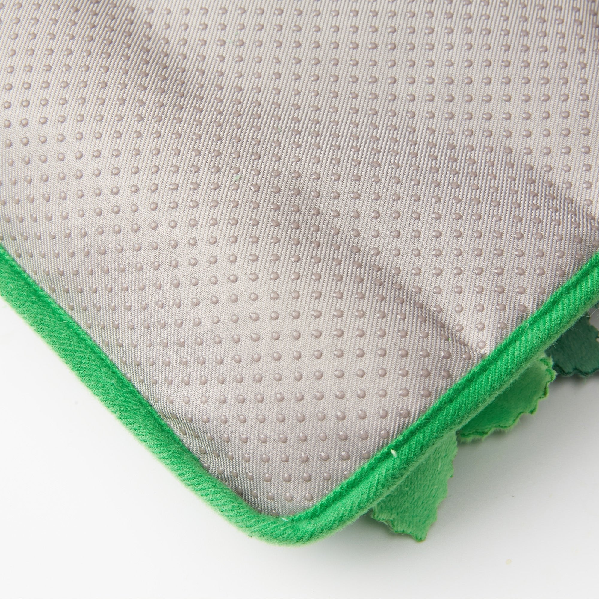 Close-up of the Dog Puzzle Grass Sniffle Mat by Puzzle Feeder™, featuring a gray fabric surface with a textured, dotted pattern and bordered by green edges, designed for sensory stimulation.