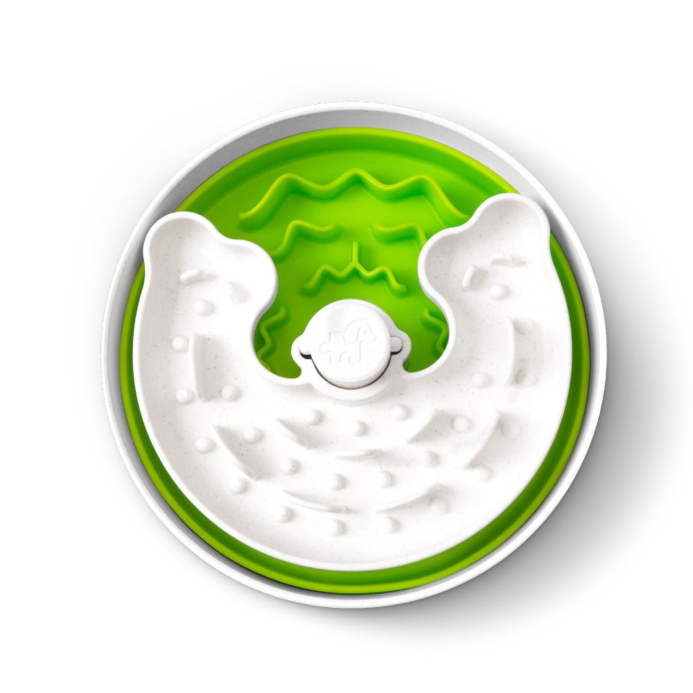 The Puzzle Feeder™ Junior, a green round bowl featuring a white maze-like pattern and a small elephant logo at its center, is designed to encourage healthy eating habits for small and medium-sized dogs.