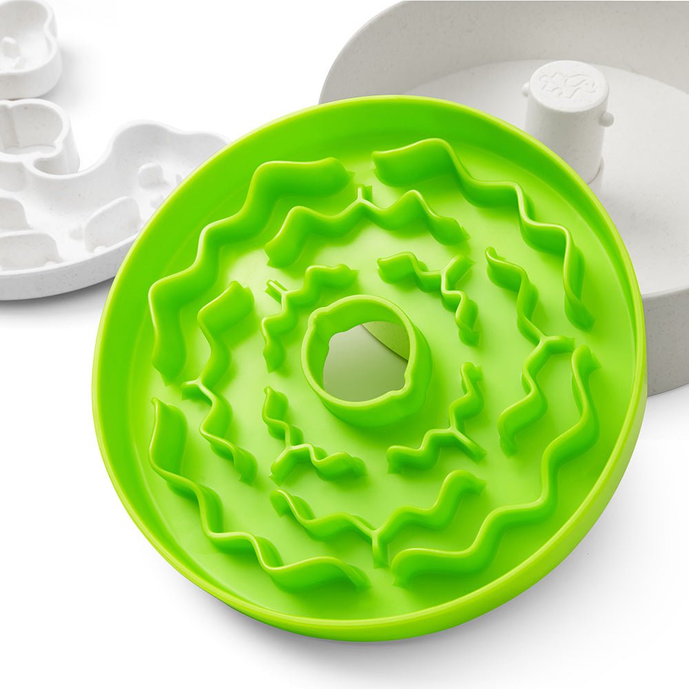 Puzzle Feeder™ Junior for small and medium dogs in green features a spiral design with a central opening, promoting healthy eating habits. Ideal for small dogs and puppies, it is displayed on a white surface.