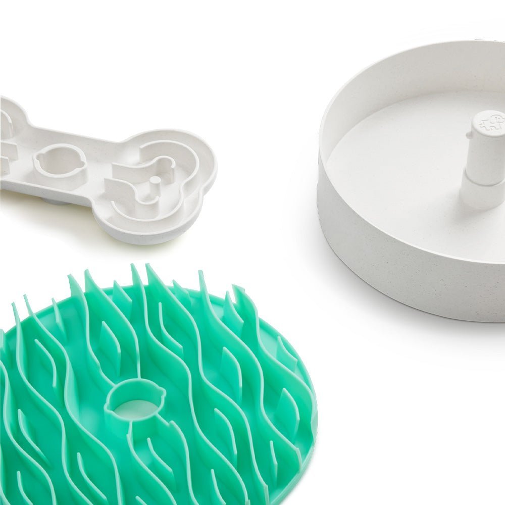 Pet feeding accessories include the Puzzle Feeder™ Wave in lawn-green, designed for dogs to slow feeding more effectively than a traditional slow feeder, along with a white puzzle feeder that promotes healthy digestion and a round white bowl featuring a central divider.