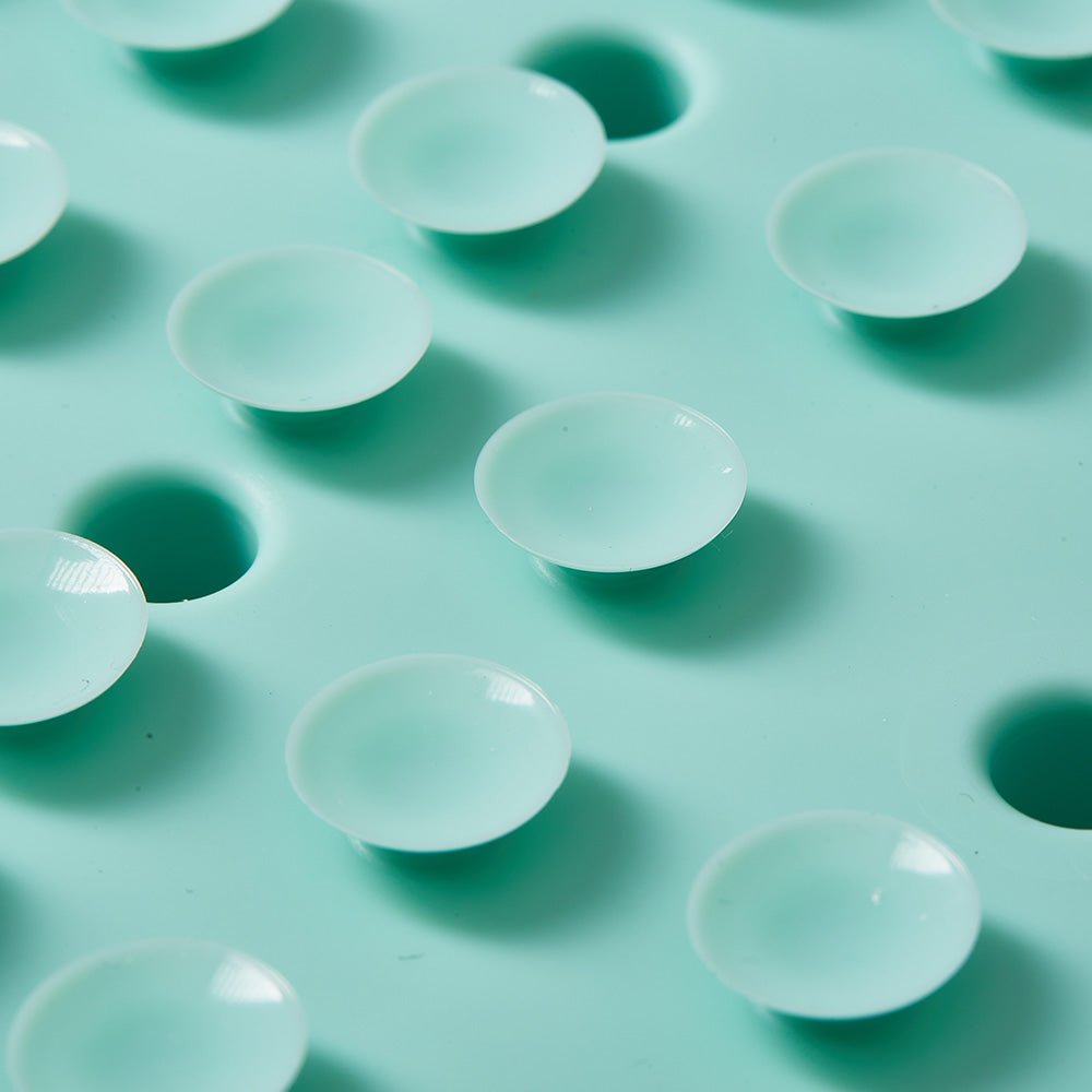 Close-up of transparent suction cups on a green surface with matching circular indents, featuring an antislip design inspired by biomimetic principles, as seen in the Puzzle Feeder™ Dog Puzzle Mat - Slow Feeding Mat.