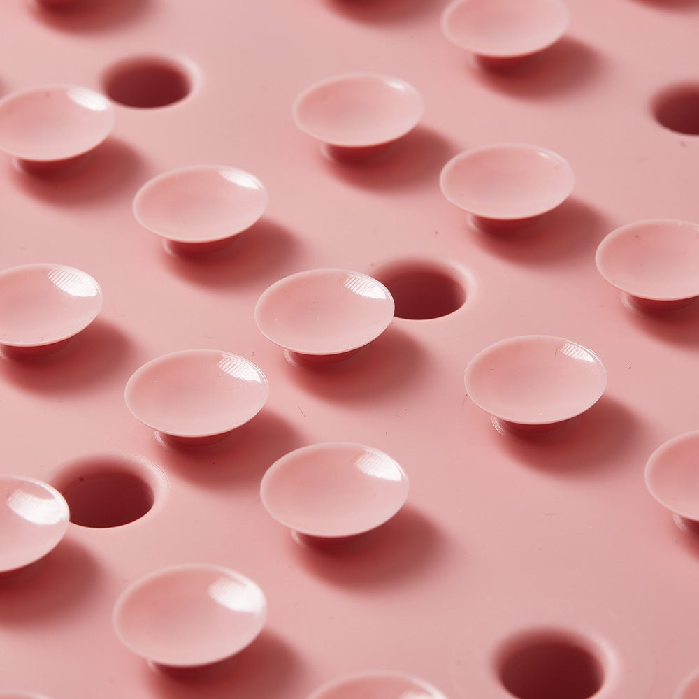 Close-up of the Dog Puzzle Mat - Slow Feeding Mat (Pink) by Puzzle Feeder™, featuring a pink surface with round, dome-shaped indentations and some raised dots, resembling a biomimetic design.