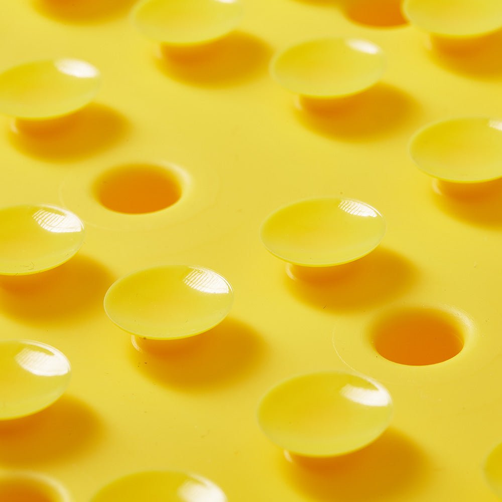 Close-up of the Puzzle Feeder™ Dog Puzzle Mat - Slow Feeding Mat in yellow, with raised, glossy circular bumps arranged in a grid pattern to highlight its antislip suction cup feature for enhanced grip.